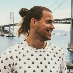 Profile of man smiling with a bridge and water in the background