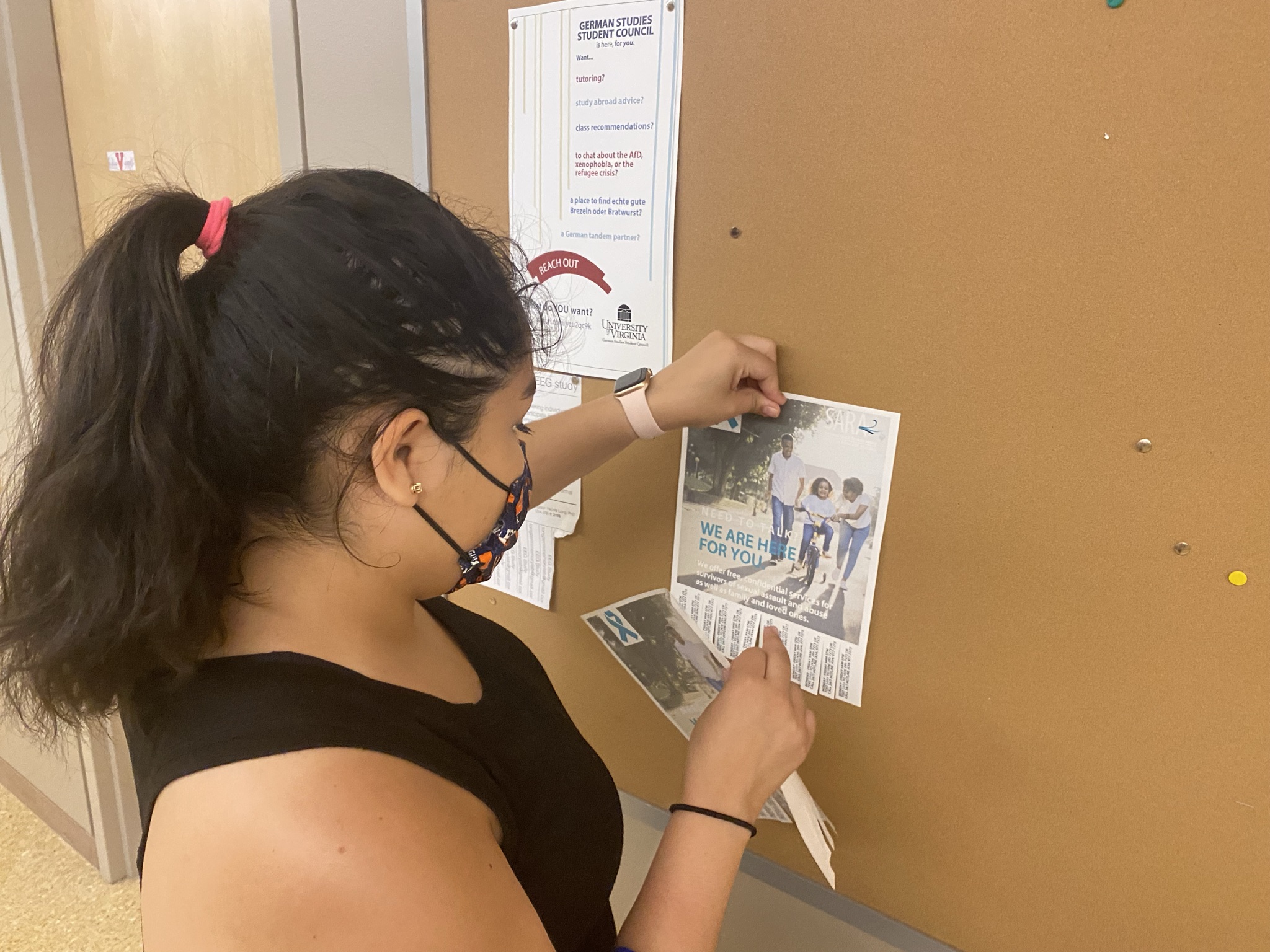A student posts a flyer for the Sexual Assault Resource Agency on a bulletin board in New Cabell Hall. 