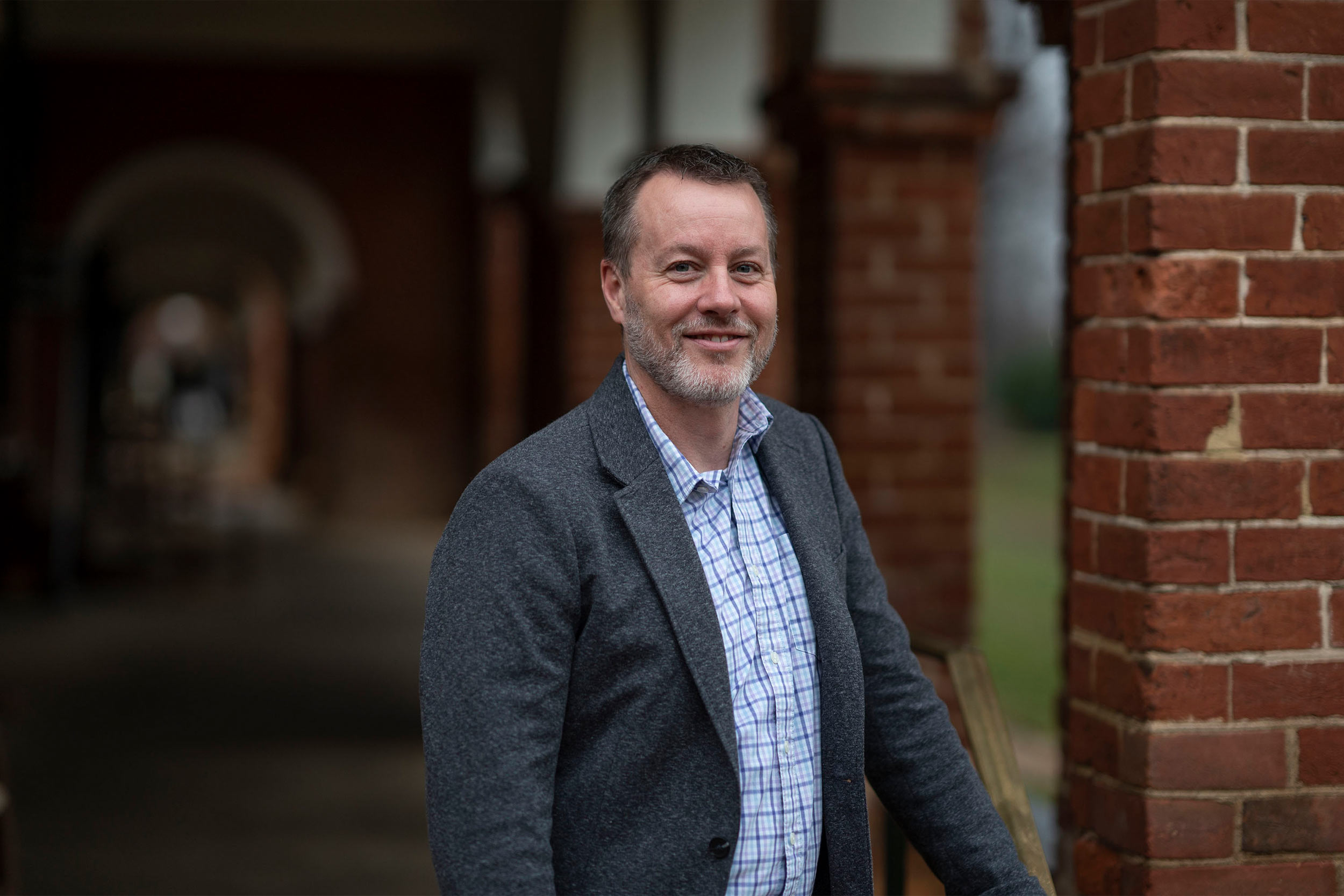 Michael Palmer posing in front of bricks around grounds
