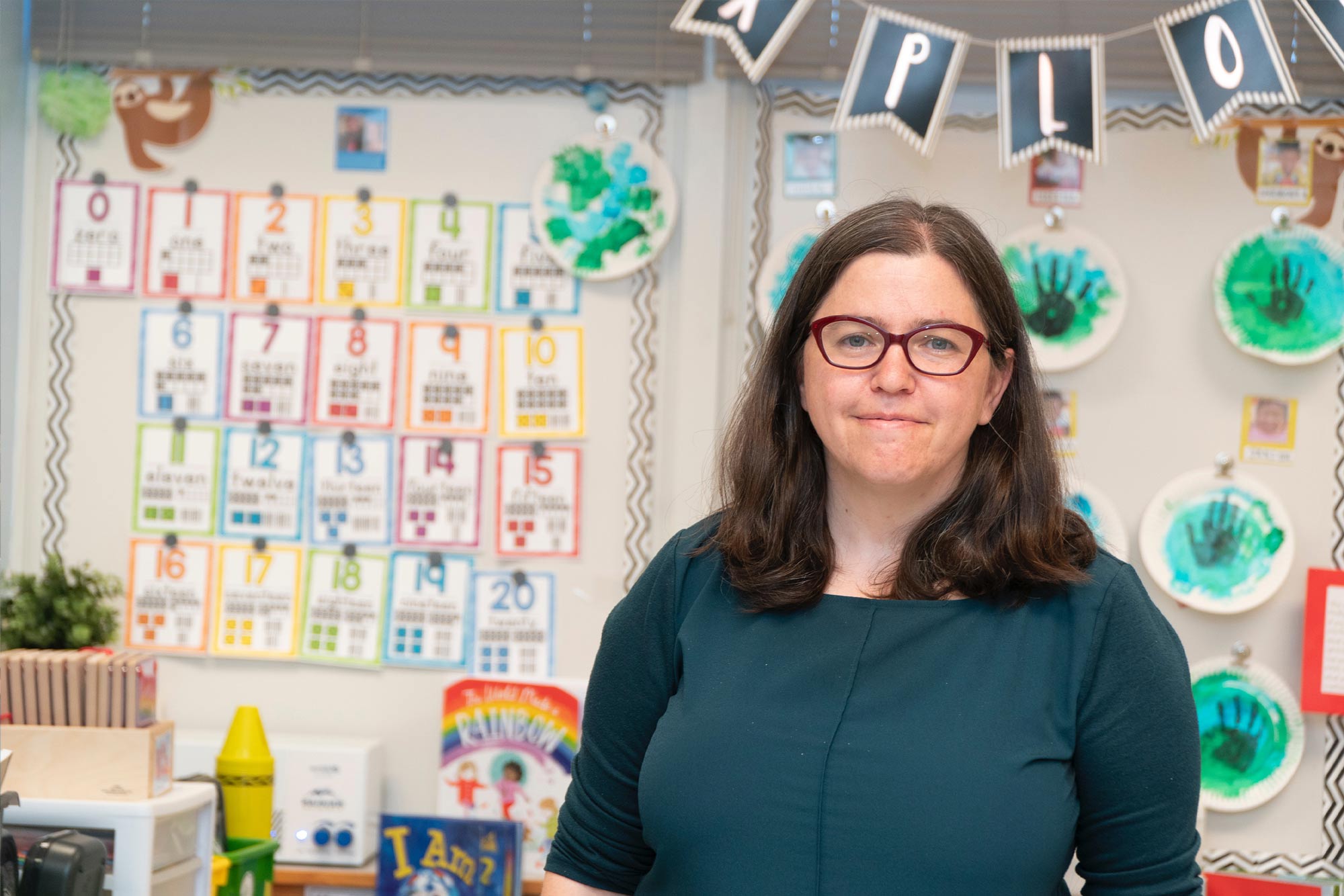Daphna Bassock stands in a classroom with colorful thing behind her