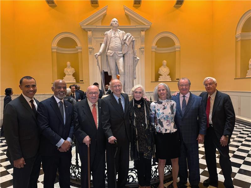 A group of people pose for a photo of a Thomas Jefferson statue at the Virginia House of Delegates